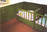 A photo of two green baby cribs... and one has a baby in it.